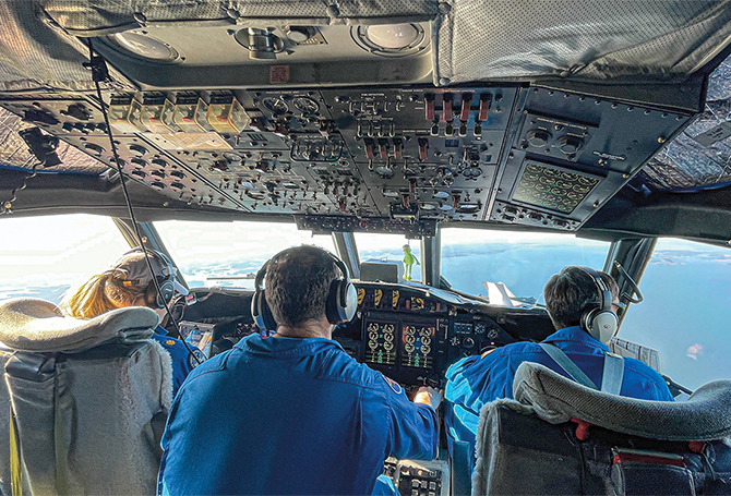 Enlargeable photo of plane cockpit interior with three pilots at the controls