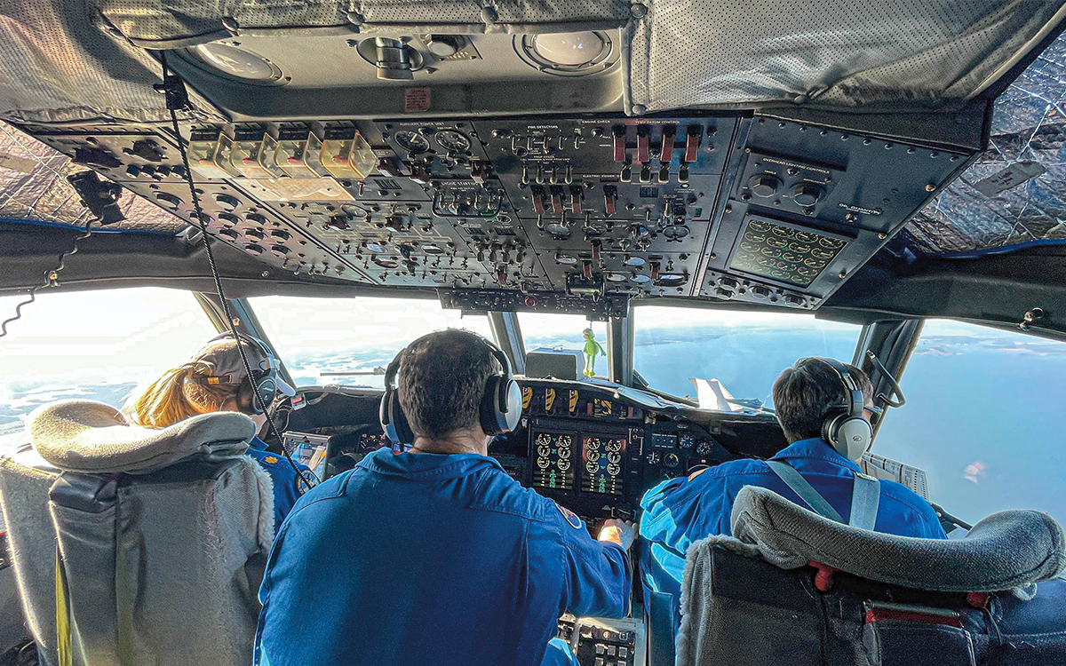 Plane cockpit interior with three pilots at the controls