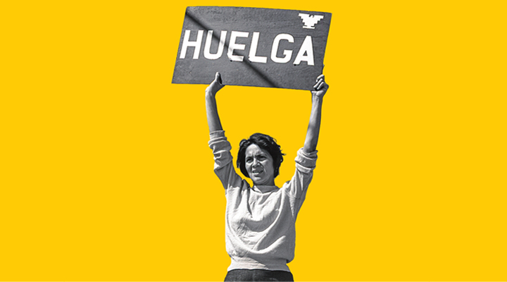 A woman holding up a sign with the text "Huelga"