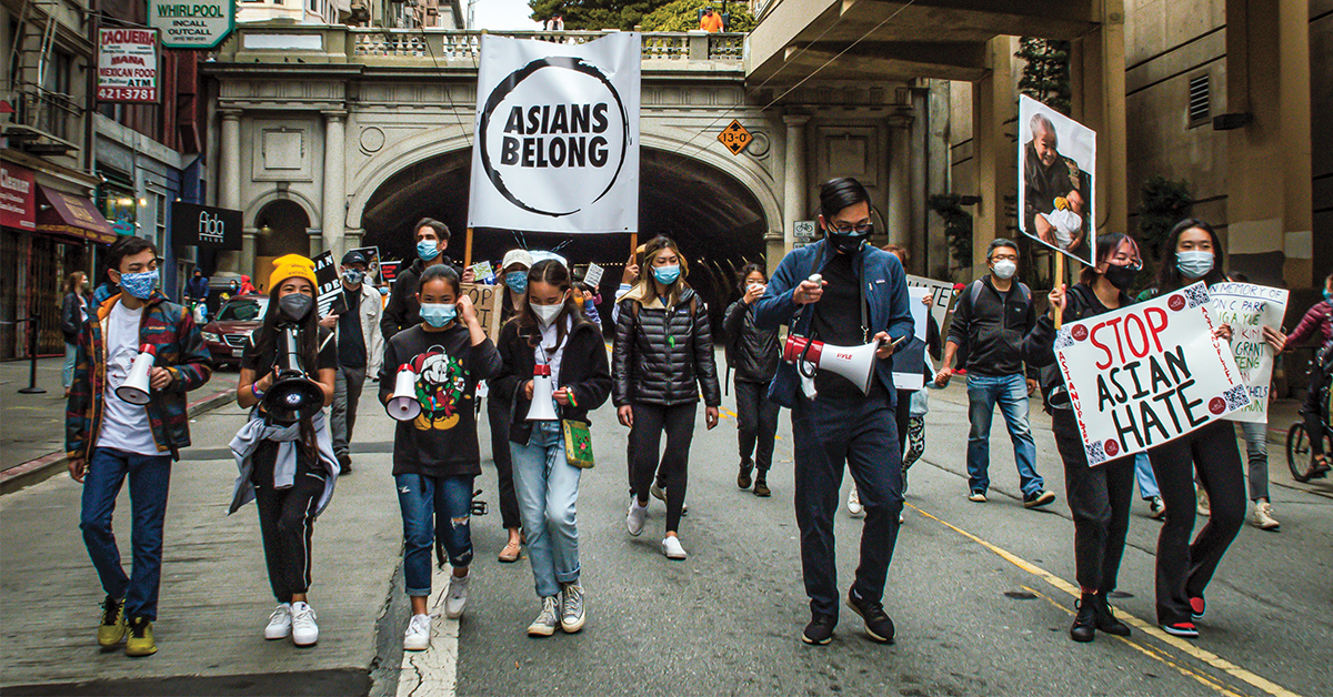 Ashlyn marching with other teens with signs saying "Asians Belong"