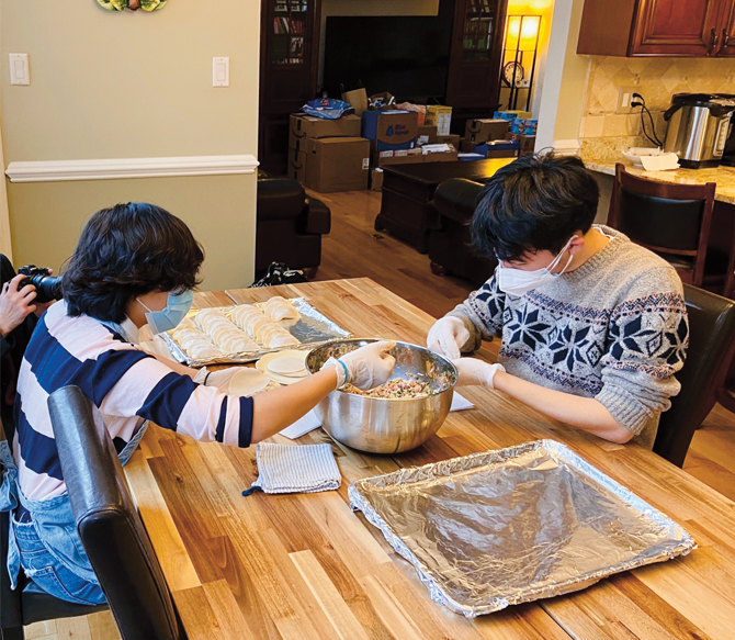 Enlargeable photo of a young man and his sister with gloves on and their hands in dumpling filling
