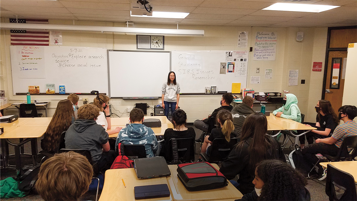 A young woman speaking in front of a class of other teens
