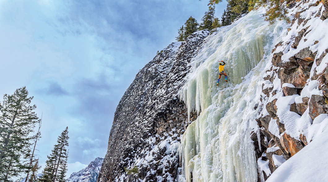 Photo of a person ice climbing on the side of a mountain