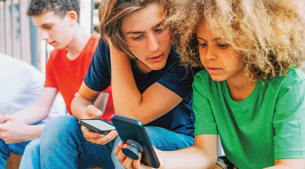 Image of three people sitting down and using their phones