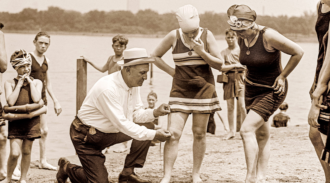 Sepia tone image of a person measuring length from knee to bottom of bathing suit of women swimming